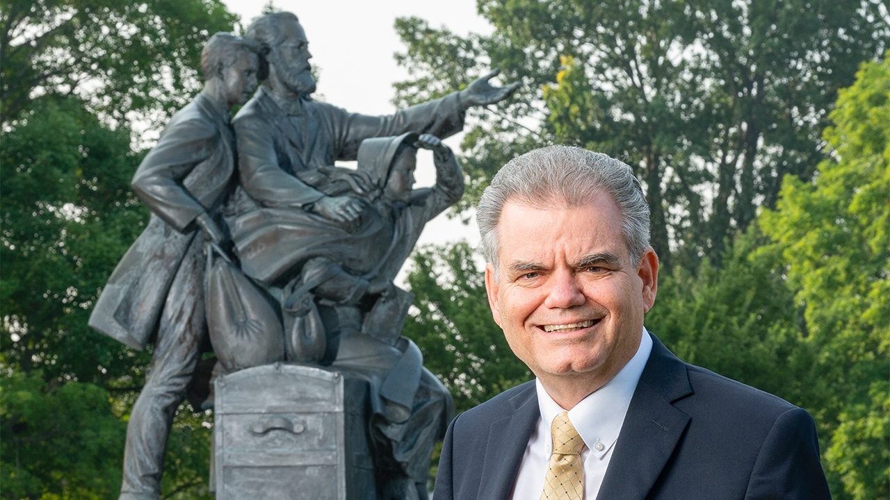 Two people walk past a statue on campus.